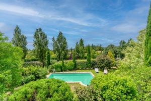 an outdoor swimming pool surrounded by trees and bushes at Clos des Hérissons - Chambres d'Hôte - Piscine & jardin in Lauris