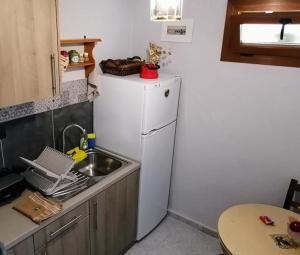 a small kitchen with a white refrigerator and a sink at Roppas Studios Nostos in Kato Gatzea