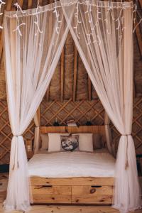 uma cama num quarto de palha com cortinas em VasaRojaus Jurta em Birstonas