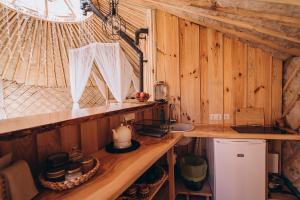 a kitchen with wooden walls and a counter in a room at VasaRojaus Jurta in Birštonas