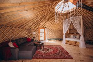 a living room with a couch and a bed in a yurt at VasaRojaus Jurta in Birštonas
