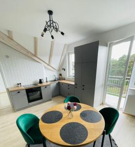 een keuken met een houten tafel en groene stoelen bij Apartament z widokiem na wydmę in Ustka