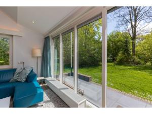 een woonkamer met een blauwe bank voor een raam bij Attractive vacation home with spacious garden in Vrouwenpolder