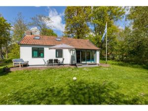 uma pequena casa branca com uma mesa e um guarda-chuva em Attractive vacation home with spacious garden em Vrouwenpolder