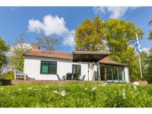 een wit huis met een paraplu in het gras bij Attractive vacation home with spacious garden in Vrouwenpolder