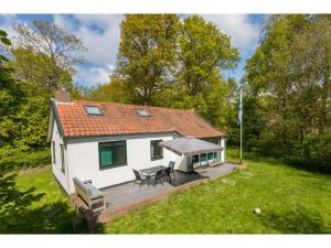 een klein wit huis met een veranda en een terras bij Attractive vacation home with spacious garden in Vrouwenpolder