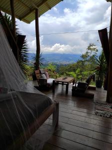 a porch with a bed and a table and chairs at Hacienda Monteclaro in Turrialba