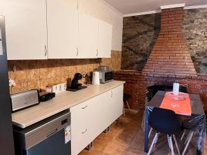 a kitchen with white cabinets and a table and a brick wall at Casa Amarela in Loulé