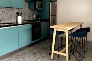 cocina con mesa de madera y armarios azules en 118 SUITES DONCELES CENTRO HISTÓRICO CDMX, en Ciudad de México