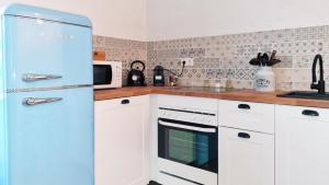 a kitchen with white cabinets and a blue refrigerator at Apartment Kerbholz - zwischen Südschwarzwald und Schweiz in Klettgau