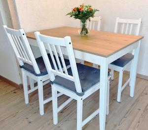 a wooden table with three chairs and a vase of flowers at Apartment Kerbholz - zwischen Südschwarzwald und Schweiz in Klettgau
