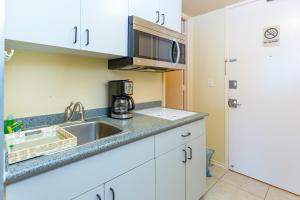 a kitchen with a sink and a microwave at Ocean & Diamond Head View Studio at Waikiki in Honolulu
