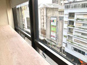 - deux fenêtres dans une chambre avec vue sur un bâtiment dans l'établissement Apart hotel Ciudad de Bs As, à Buenos Aires