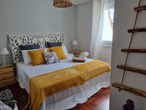 a bedroom with a bed with yellow and blue pillows at Chalet en el centro de Baiona con vistas in Baiona +29 photos