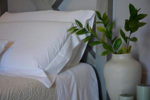 a white vase with a plant in it next to a bed at Dimora Lilla in Polignano a Mare