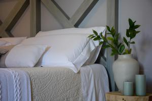 a bed with white pillows and a vase on a table at Dimora Lilla in Polignano a Mare
