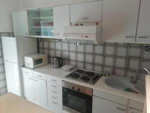 a kitchen with white cabinets and a sink and a microwave at Pine Apartment in Gevgelija +16 photos