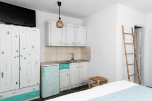 a kitchen with white cabinets and a sink and a ladder at Anna's Apartments in Mikonos