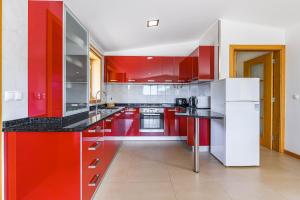 eine Küche mit roten Schränken und einem weißen Kühlschrank in der Unterkunft Escolinha de France in France