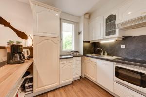 a kitchen with white cabinets and a window at The Parc des Raisses - T2 for 4 people in Annecy