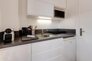 - une cuisine avec des placards blancs et un évier dans l'établissement Le Mont Blanc - Charmant T1 idéal pour 2 personnes avec balcon, à Annecy