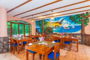 プエルトアヨラにあるGrand Hotel Leon Marino Galapagosの木製のテーブルと椅子、壁画のあるレストラン