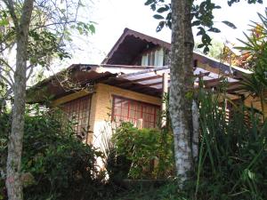 een huis met rode ramen in het bos bij Chalé Pakere Montanha Lumiar - Conforto a mais de 1000 metros de altitude junto a natureza, lareira, wifi, piscina, sauna e água de nascente in Lumiar
