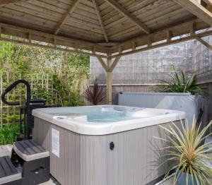 uma banheira de hidromassagem num pátio com uma pérgola em The Studio Castlerock with Hot Tub em Coleraine