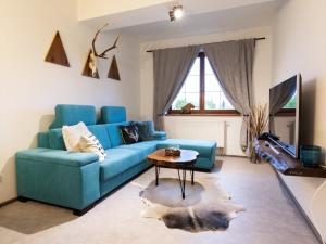- un salon avec un canapé bleu et une table dans l'établissement TatryView Apartments by KingDubaj PREMIUM, à Veľká Lomnica