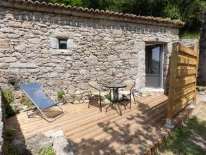 een houten terras met een tafel en stoelen naast een stenen muur bij Gîte Mortagne-sur-Sèvre, 1 pièce, 2 personnes - FR-1-426-484 in Mortagne-sur-Sèvre