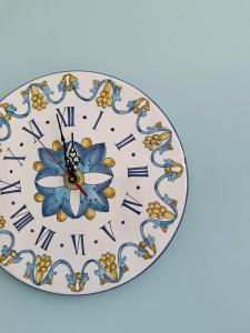 a clock with a blue flower and roman numerals at B&B Margherita 2 in Marina di Camerota