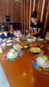 una mujer y dos niños sentados en una mesa con comida en Canto do Sabiá PETAR Hospedagem Familiar en Iporanga