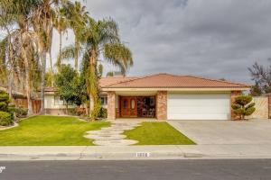 a house with a garage and palm trees at Cozy Hygge Home Centrally Located 2 King Beds in Bakersfield