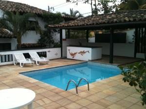 a swimming pool with two chairs and a gazebo at Casa em Búzios Geribá in Búzios