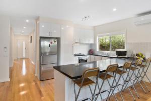 a kitchen with a black counter top and chairs in it at Coastal Cootamundra in Capel Sound