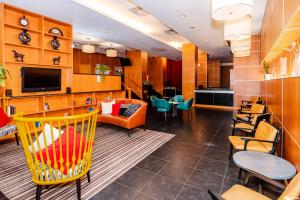 新卡羅頓的住宿－梅特羅彭華盛頓北飯店，一间设有黄色椅子和电视的等候室