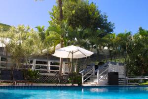 a swimming pool with an umbrella and chairs and trees at Club Seabourne Hotel in Culebra