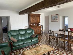 a living room with a green leather couch and a table at Gîte Montaiguët-en-Forez, 5 pièces, 8 personnes - FR-1-489-371 in Montaigüet-en-Forez