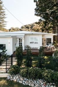 una casa blanca con una valla delante en The Patonga Cottage, en Patonga