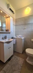 een badkamer met een wastafel, een toilet en een spiegel bij Apartment Sea view in Vrboska +11 foto's