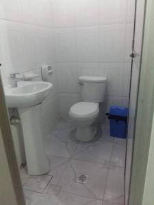 a white bathroom with a toilet and a sink at Hostal Flores in La Paz