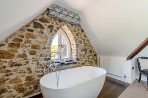 a bath tub in a room with a stone wall at Rhodewood Lodge in Saundersfoot +54 photos