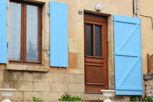 a building with blue shutters and a door at Maison accueillante à Saint-Amand-en-Puisaye avec jardin in Saint-Amand-en-Puisaye