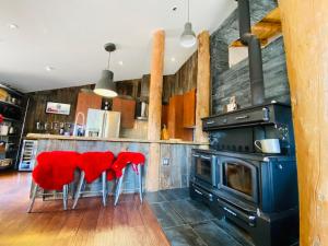 a kitchen with red chairs and a stove at Artemis Log Cabin with Spa & Mountain View in Sainte-Lucie-de-Doncaster