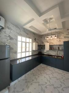 a large kitchen with blue cabinets and a window at فيلا تل الورد in Ibri
