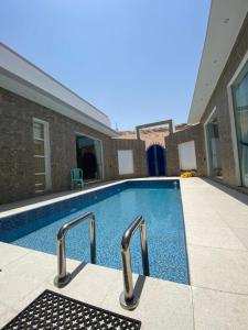 uma piscina com dois carris de metal ao lado de um edifício em فيلا تل الورد em Ibri