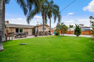 un patio con palmeras y una casa en Oceanside Rocks Family Vacation Home en Oceanside