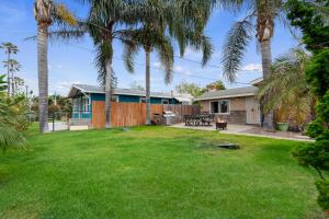 a backyard with palm trees and a house at Oceanside Rocks Family Vacation Home in Oceanside