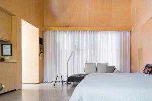 a bedroom with a bed and two chairs and a window at Buhwi Bira Byron Bay - Studio in Byron Bay