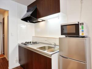 una pequeña cocina con fregadero y microondas en Condominium・yuyuki, en Yomitan